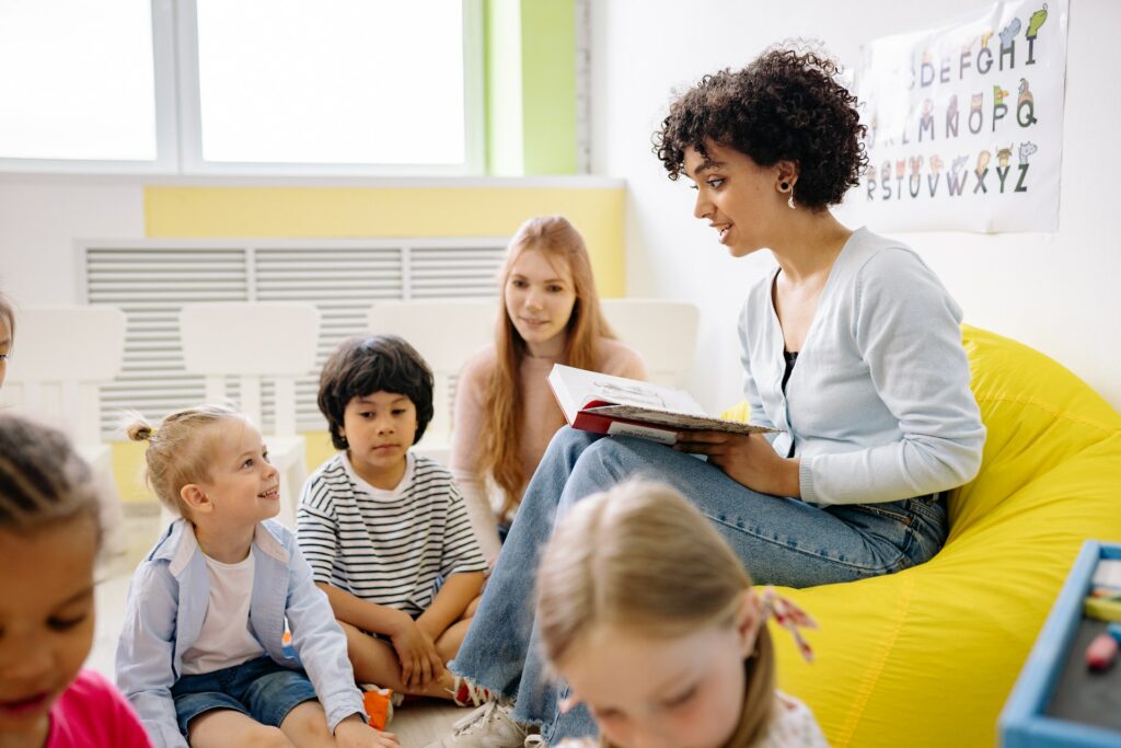 A woman reading to a class of young children, this is the foundation of reading comprehension skills as it is where most children start their reading journey