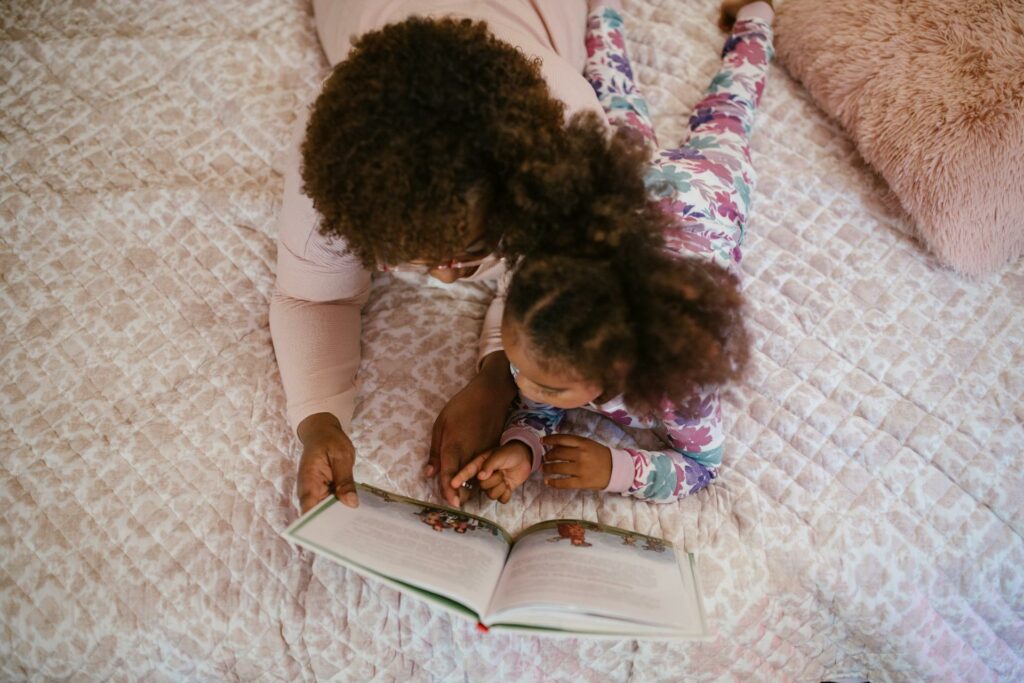 a mother reading with her daughter on the bed, parents play a large role in improving the literacy rate in South Africa
