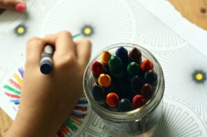 A child with a jar of crayons, play with art supplies can help nurture a child's creativity